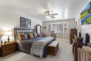 Bedroom with light carpet, a ceiling fan, baseboards, and a textured ceiling