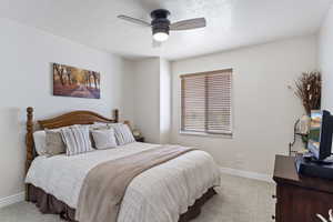 Bedroom with a textured ceiling, baseboards, a ceiling fan, and light colored carpet