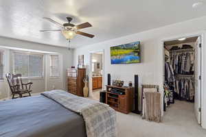 Bedroom featuring a closet, light colored carpet, a spacious closet, ceiling fan, and a textured ceiling