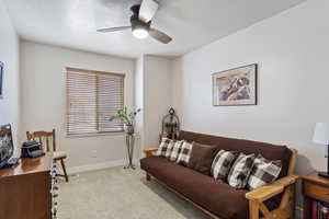 Living room featuring a ceiling fan, carpet, a textured ceiling, and baseboards