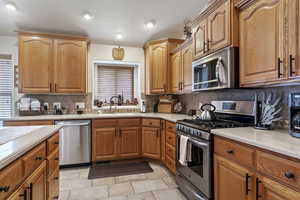 Kitchen with decorative backsplash, appliances with stainless steel finishes, light countertops, and a sink