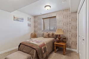 Bedroom with visible vents, baseboards, a textured ceiling, carpet flooring, and a closet