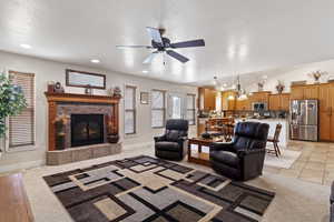 Living room with lofted ceiling, a textured ceiling, recessed lighting, baseboards, and a tiled fireplace