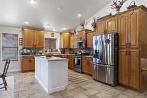 Kitchen featuring decorative backsplash, a kitchen island, brown cabinets, stainless steel appliances, and light countertops