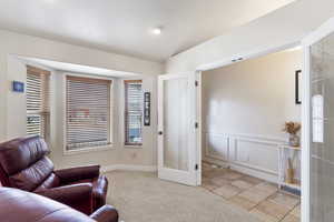 Living area with light carpet, a decorative wall, and french doors