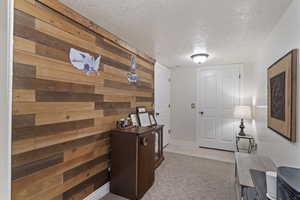 Hall with light tile patterned floors, wooden walls, and a textured ceiling