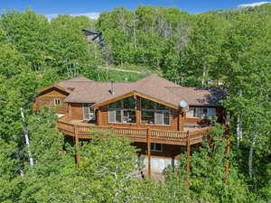 Rear view of house featuring log siding, a deck, and a shingled roof