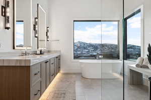 Bathroom featuring a mountain view, a soaking tub, a sink, and double vanity