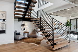 Stairway featuring baseboards, wood finished floors, and recessed lighting