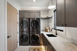 Clothes washing area featuring cabinet space, washer and dryer, a sink, and stacked washer and clothes dryer