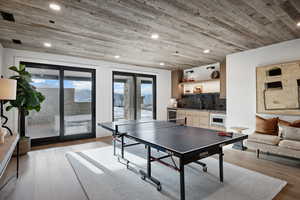 Recreation room with light wood finished floors, wood ceiling, wet bar, and a sink