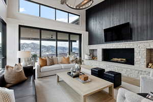 Living room with a notable chandelier, a fireplace, and a towering ceiling