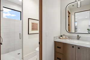 Bathroom featuring visible vents, baseboards, toilet, vanity, and a shower stall