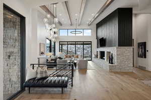 Interior space with a high ceiling, a fireplace, wood finished floors, visible vents, and beamed ceiling