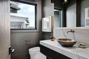 Half bathroom featuring tasteful backsplash, a wealth of natural light, vanity, and toilet