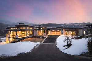 Snow covered house with driveway and a mountain view