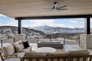 View of patio with a mountain view, an outdoor living space with a fire pit, a balcony, and a ceiling fan