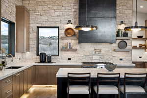 Kitchen with light stone countertops, a kitchen bar, open shelves, and a sink