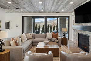 Living room featuring wooden ceiling, light wood-style floors, recessed lighting, and a stone fireplace