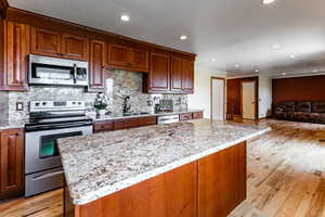 Kitchen featuring light stone countertops, tasteful backsplash, stainless steel appliances, and a sink