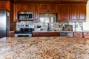 Kitchen featuring stainless steel appliances, brown cabinetry, and a sink