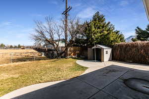 View of yard with a storage shed, a fenced backyard, an outbuilding, and a patio