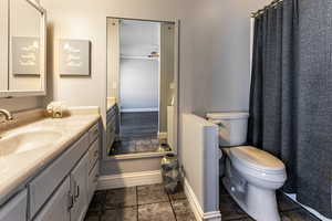 Bathroom featuring baseboards, vanity, toilet, and tile patterned floors