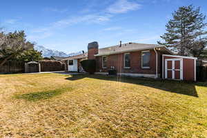 Back of property featuring a shed, fence, brick siding, and central air condition unit