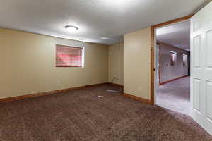 Empty room featuring carpet flooring, a textured ceiling, and baseboards