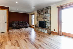 Living room featuring a fireplace, light wood finished floors, recessed lighting, ornamental molding, and baseboards