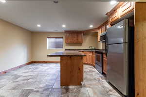 Kitchen with recessed lighting, stainless steel appliances, a sink, baseboards, and a center island