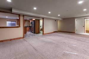 Interior space with light carpet, recessed lighting, and freestanding refrigerator