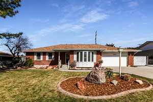 Ranch-style home with brick siding, concrete driveway, a front yard, fence, and a garage