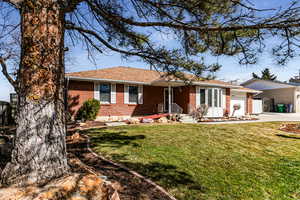 Single story home with driveway, a shingled roof, an attached garage, a front lawn, and brick siding