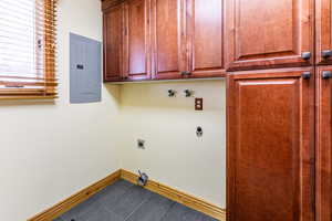 Laundry room with cabinet space, electric panel, baseboards, and electric dryer hookup