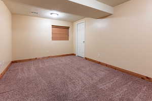 Unfurnished room with a textured ceiling, carpet, visible vents, and baseboards