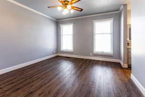 Unfurnished room with baseboards, ornamental molding, ceiling fan, and dark wood-style flooring