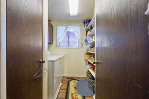 Laundry room with cabinet space, a textured ceiling, wood finished floors, independent washer and dryer, and baseboards