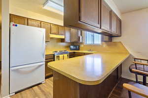 Kitchen featuring freestanding refrigerator, a peninsula, black microwave, a sink, and range with electric stovetop