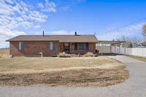 Ranch-style home with brick siding, a shingled roof, fence, an attached carport, and driveway