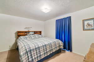 Carpeted bedroom with a textured ceiling and baseboards