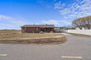 View of front facade with driveway, fence, a front lawn, a carport, and brick siding