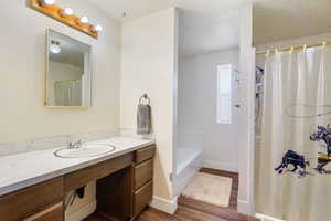 Bathroom with curtained shower, a textured ceiling, vanity, wood finished floors, and baseboards