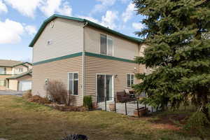 Rear view of house with a garage, a yard, and a patio