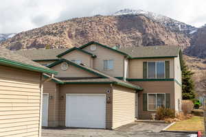 View of front facade with a shingled roof, an attached garage, and a mountain view