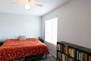 Carpeted bedroom with window, baseboards, and a ceiling fan