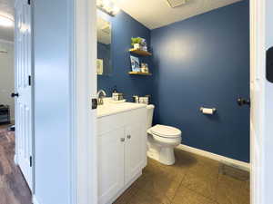 Bathroom featuring baseboards, toilet, tile patterned floors, a textured ceiling, and vanity