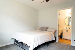 Bedroom featuring a ceiling fan, carpet flooring, ensuite bath, and baseboards