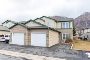 View of front of property with aphalt driveway, a mountain view, and a front lawn