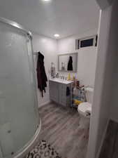 Bathroom featuring a stall shower, vanity, toilet, and wood finished floors